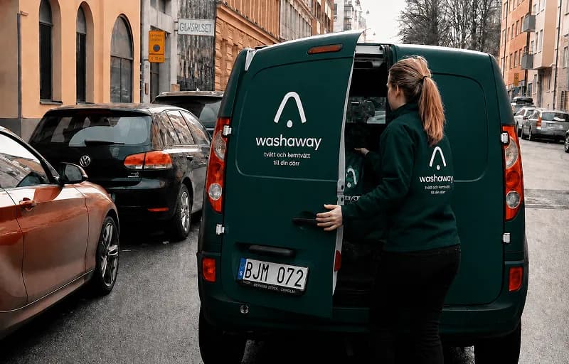 Washaway-chaufför lastar tvättpåsar i leveransbilen